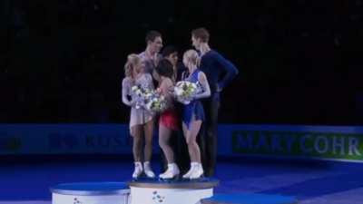 2nd and 3rd place winners of the World Figure Skating Championships help to lift the champion for podium photo