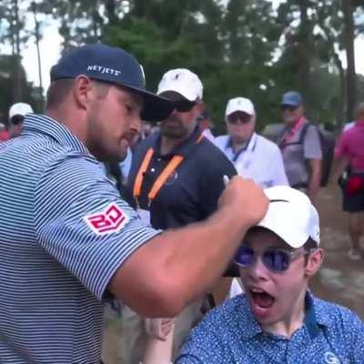 Bryson signing a fans hat on his way to the next hole, a great gesture