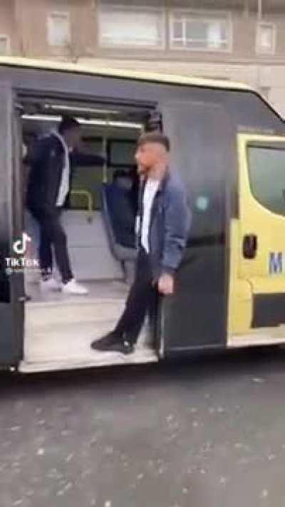 Someone hanging from the door of a bus