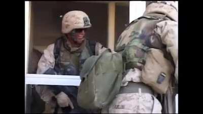 Marines find an insurgent hiding inside of a large building in Fallujah. They break the window and give him a grenade as a gift. Afterwards they make entry into the building and finish clearing it.