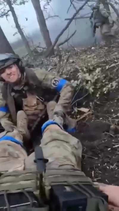 An American volunteer under fire helps his wounded Canadian comrade.

 Ukraine, February 2024.