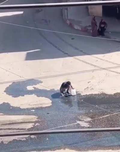 “A desperate Palestinian collects spilled water after Israel’s attack destroyed the neighborhood's water tank.“