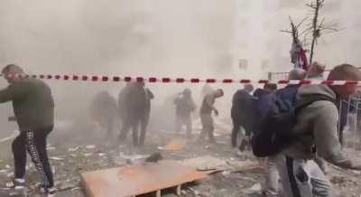 Onlookers scatter as more of the Belograd building collapses during rescue efforts. 