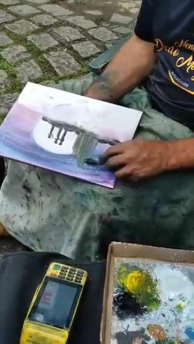 A street craftsman making paintings with his hands.