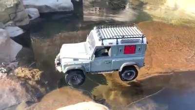 A jeep drives across an icy lake in the mountains