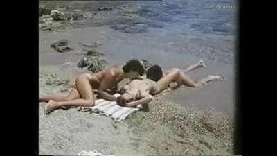 woman gets orally pleasured by two men on the beach (unknown)