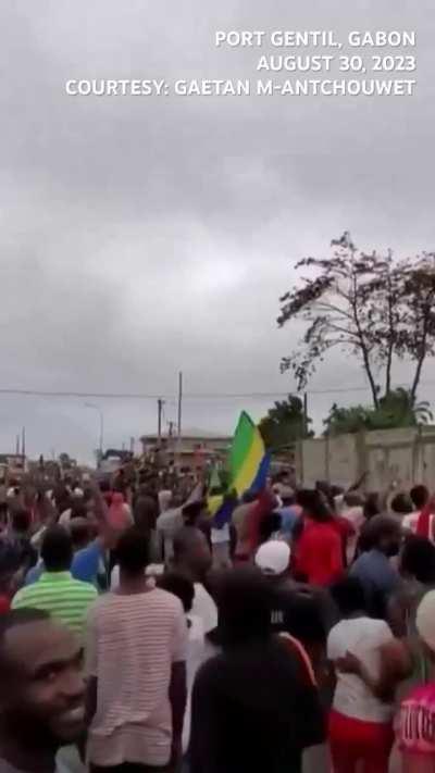 People of Gabon cheer an army convoy after the Republican Guard took over