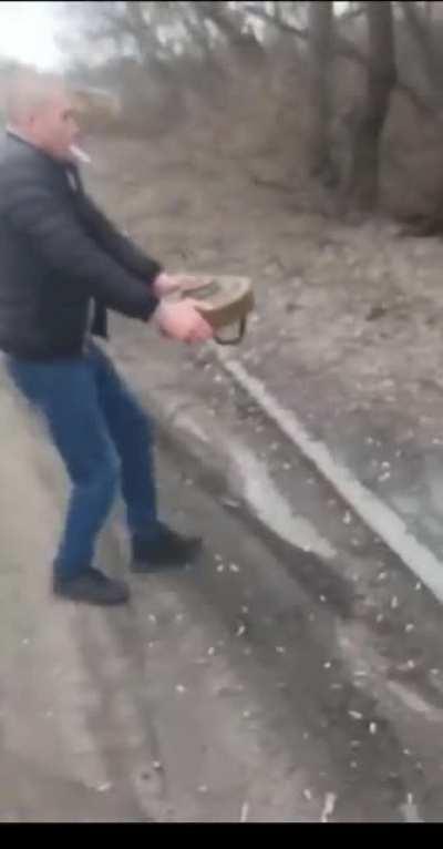 Ukrainian civilians casually remove active landmine from a bridge.