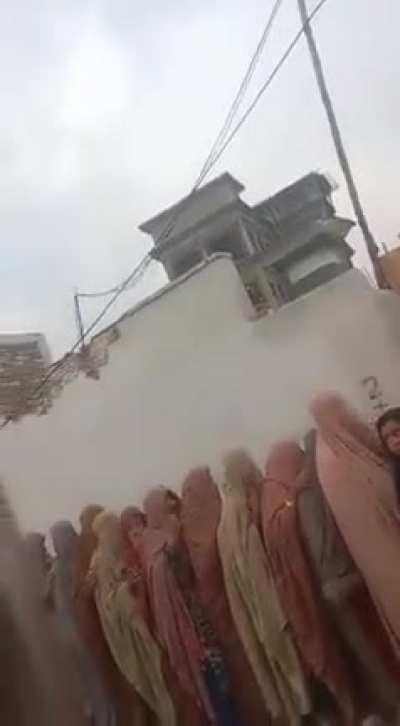 People standing in line for free flour outside a government distribution facility.