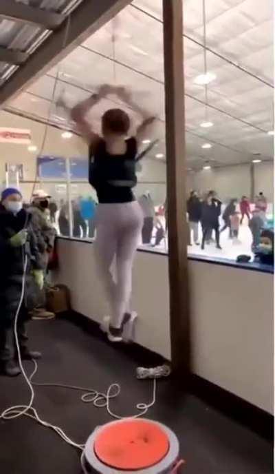 A coach, and a young ice skater using a figure skating spinner.