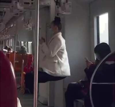 Woman swings off a subway handrail by her hair.