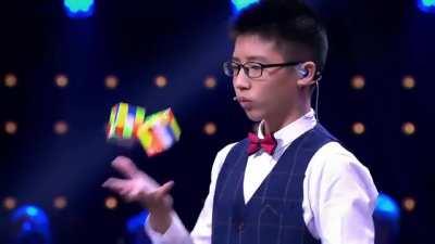 Asian teen solving 3 rubik's cubes while juggling.