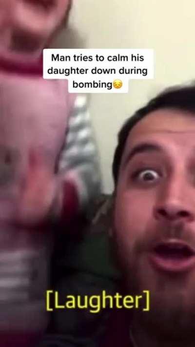 Super dad calming his daughter and making her laugh while the bombs in blast in the country