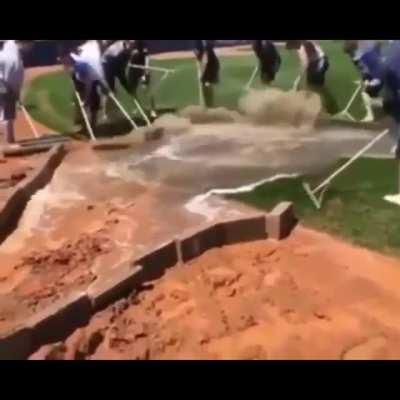 Players rake water from the field into a drain