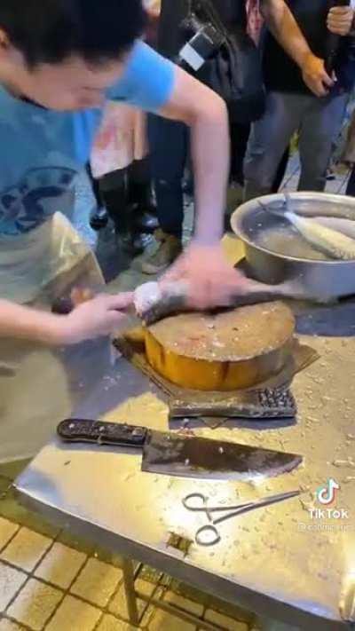 Guy cutting and removing the guts from a fish, in the coolest way possible