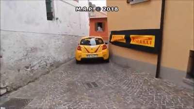 Rally cars squeezing past through narrow street