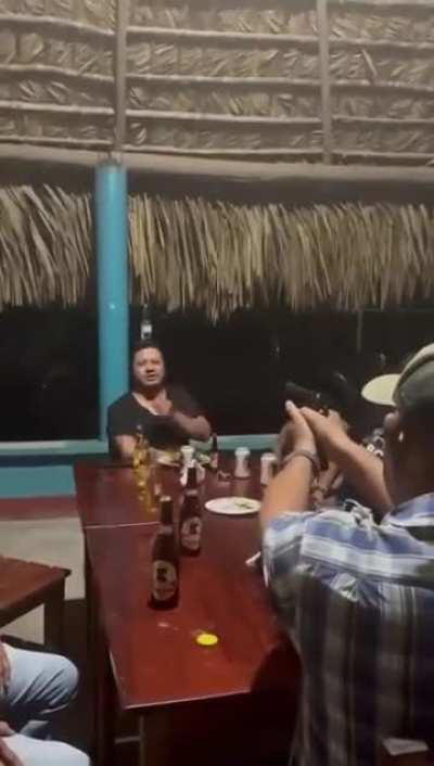 Man shoots a bottle off his friend's head.