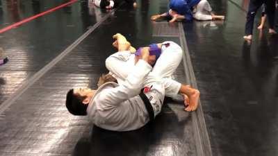 Coach Timothy Lee Peterson promoting student Kaiwi to purple belt while rolling