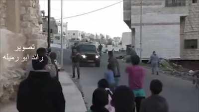 Israeli soldiers throw a disabled man out of his wheelchair as he went to the assistance of a teenage girl the Israelis had just shot.