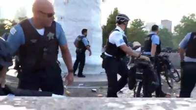 Law Enforcement Officers Protecting a Statue Getting Pelted By Rocks, Pipes, Cans and Other Objects at Chicago Protest
