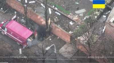 Ukrainian soldier throws grenades over a wall at Russian soldiers as they load looted valuables onto a van