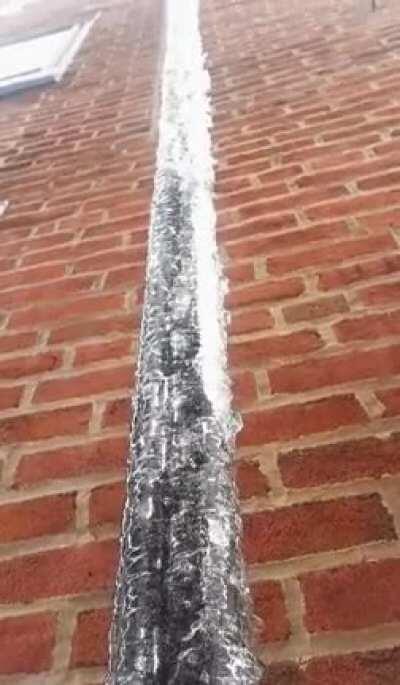 Ice on pipe melting from inside out creating a waterfall effect