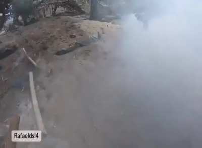 After his trench was attacked with a gas grenade, a Brazilian soldier of the International Legion throws sand over the grenade to try to stop the gas emission. Kreminna Forest, Luhansk Oblast. Probably October 2024