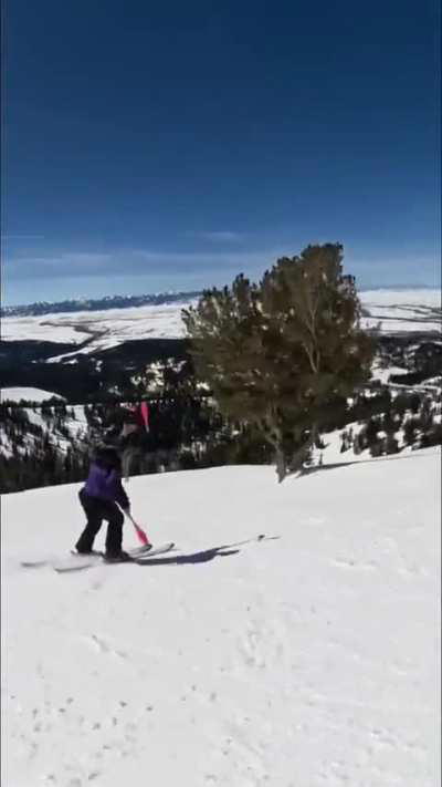 A skier goes down a snowy slope and juggles.