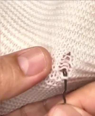 Latch hook needle mending a sweater