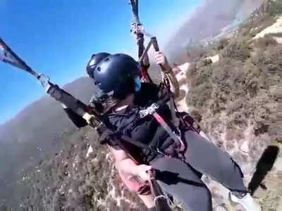 Parapenting mishap. tbf the girl could just let go of the camera and help..