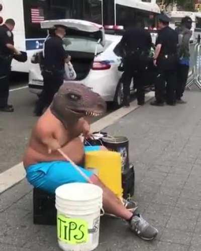 Midget dinosaur man with long legs plays buckets while man gets arrested by police