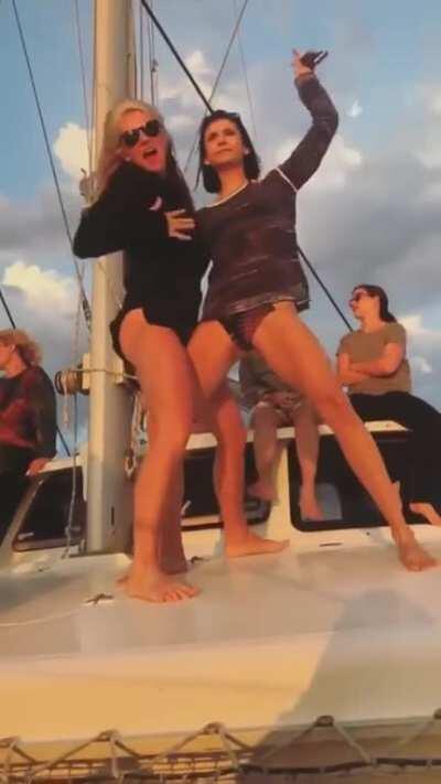 Julianne Hough and Nina Dobrev joyfully dancing on a yacht.