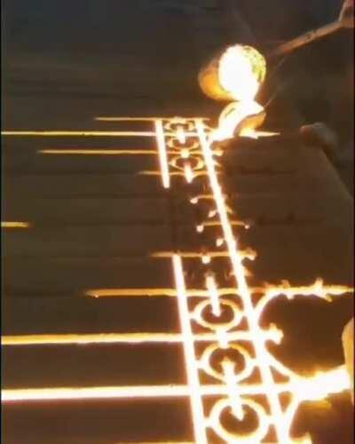 Pouring molten iron into a sand mold