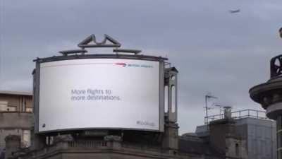 A British airline billboard in London where a kid points at a passing plane and gives you the information of the flight