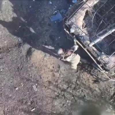 Russian soldier surrendered to a Ukrainian drone after hiding under a destroyed armored vehicle.