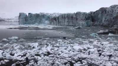 Tourists watch and scramble for cover as a huge chunk of the Breiðamerkurjökull glacier calves. The scale is hard to imagine until you see the waves.