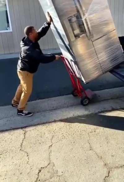 Unloading a huge fridge from a truck by himself!