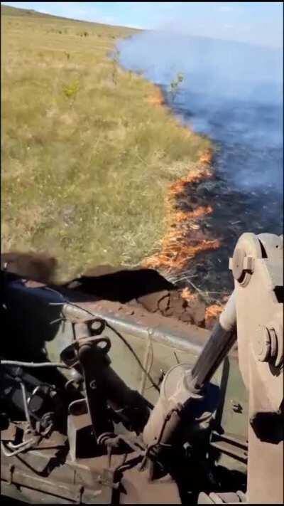 Using a bulldozer to extinguish a grass fire front