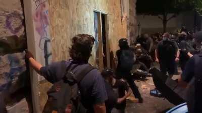 Rioters in portland tearing down the boards over the windows at the federal courthouse, then smashing windows