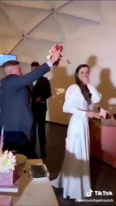 Guest destroys wedding cake and tries to throw it at the bride and groom, then gets a punch to the face.