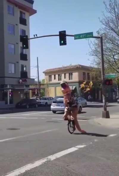 Someone in T rex costume on a unicycle playing a flaming bagpipe chasing a man down a street