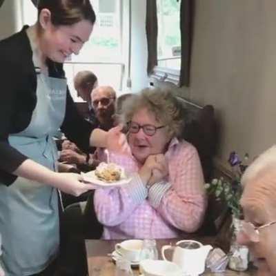 Sweet lady reacting to a free birthday cake at a diner she regularly visits.