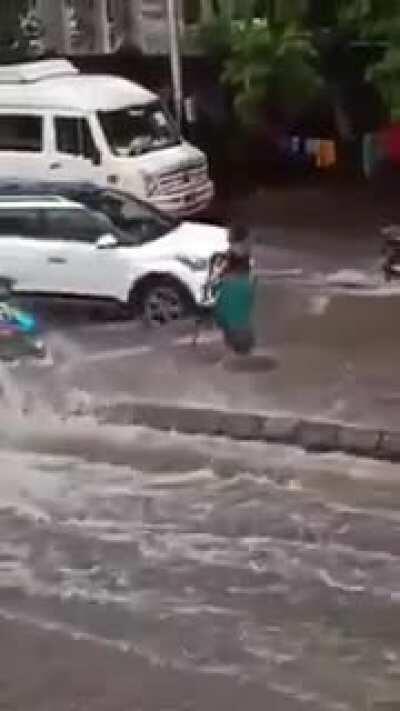 During torrential rains in Mumbai, a woman saw a manhole was open on a busy, flooded street. She stood on top — for five hours in the pouring rain — to warn drivers not to drive over it.