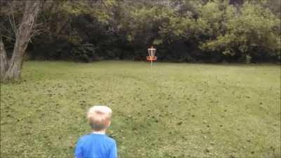 Kid hits a long disc golf shot