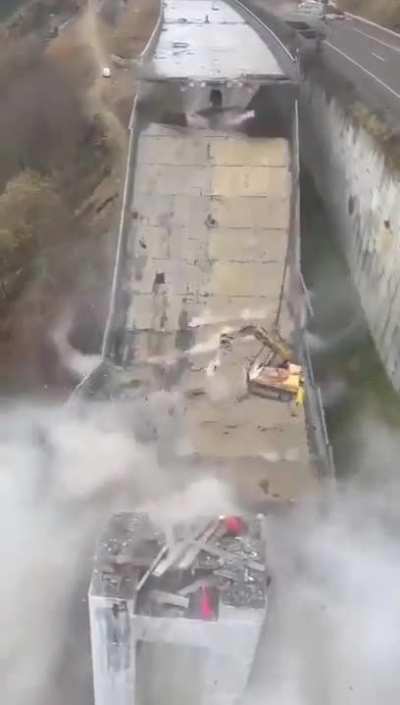 Excavator demolishing bridge.