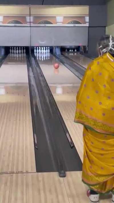 Grandma goes bowling in saare with mask on.