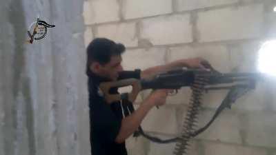 A Noor al-Ghouta fighter lays down fire with an LMG on a building in Qaboun, Syria (June 2013)