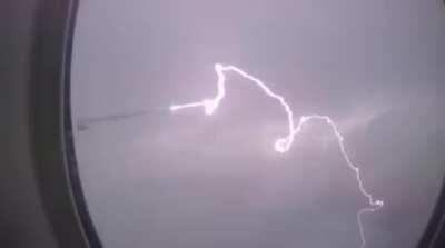 Lightning strikes the wing of a plane over Paris, France.