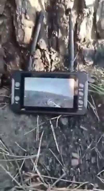 Russian soldiers in Ukraine use an FPV monitor to view the feed from Ukrainian drones attacking their position. The explosion from the hit can be heard close by.