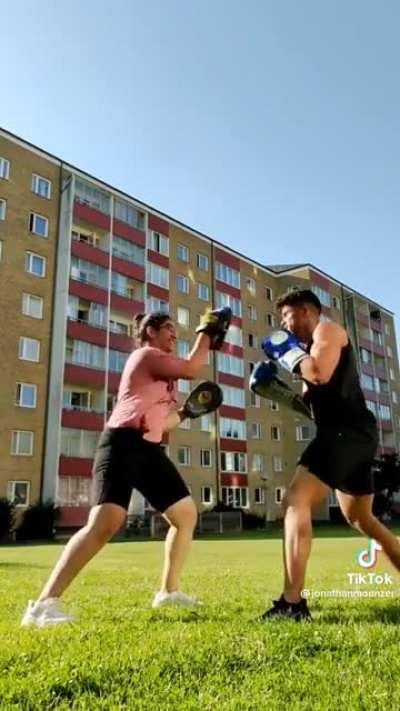 Guy teaches his sister to be his boxing trainer. She excels at the task.